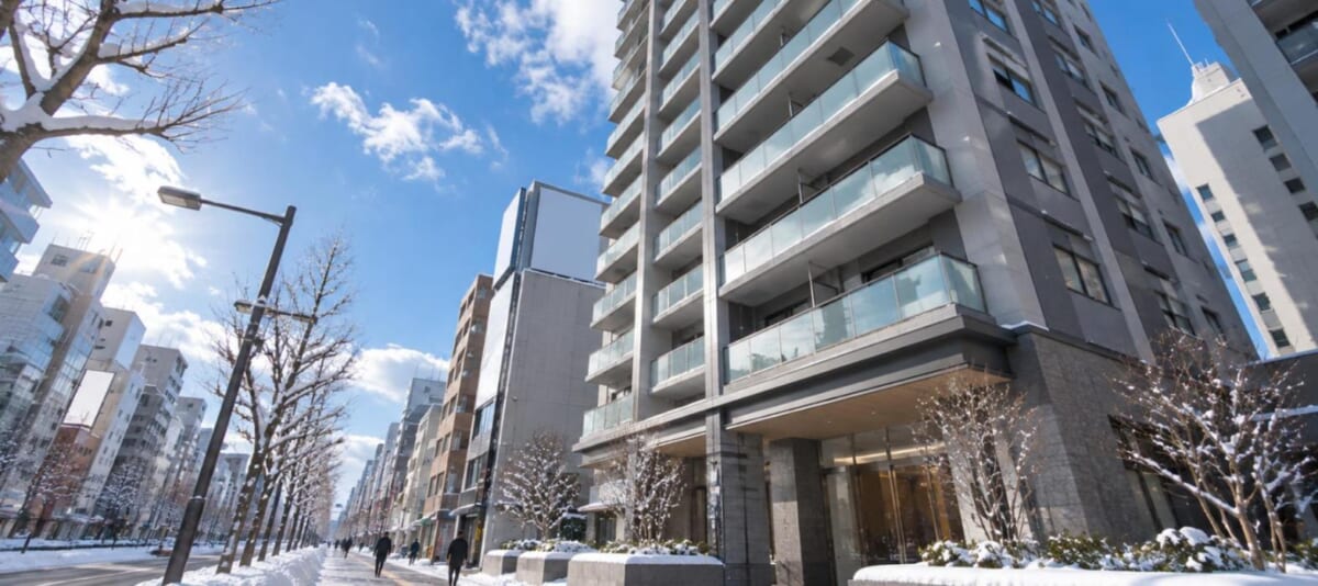 大通りに面した高層マンションを歩道から見上げた構図（冬の晴天）